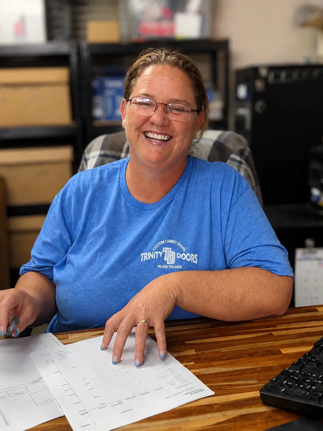 A smiling Trinity Doors office team member reviewing an order at the front desk in Vidor, TX